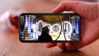 Hand holding the iPhone 14 Pro Max, one of the best iPhones for photography, above a desk